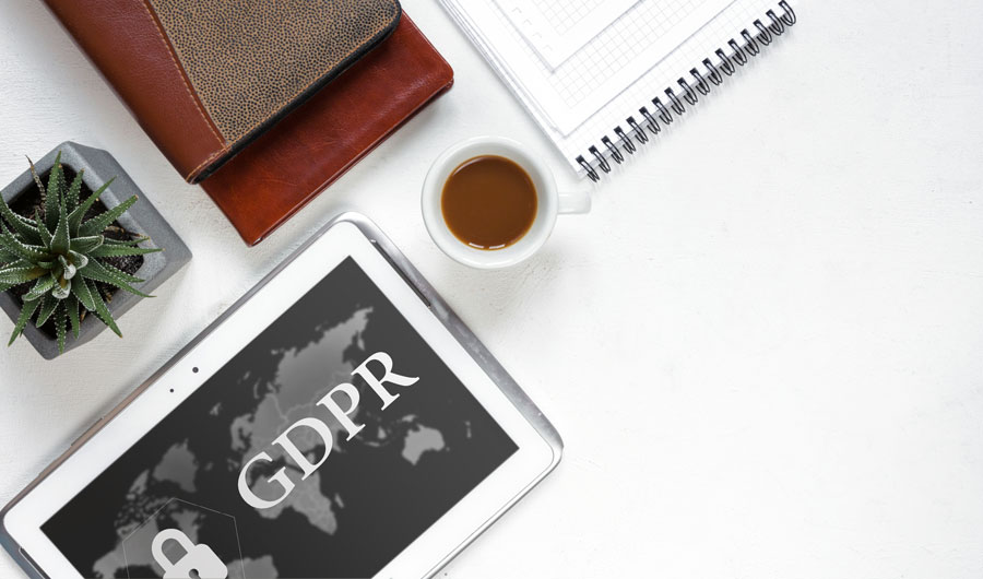 Tablet mit GDPR-Worldmap, Kaffeetasse, Notizbuch und Sukkulente auf Schreibtisch, Thema Datenschutz im Webdesign nach DSGVO.